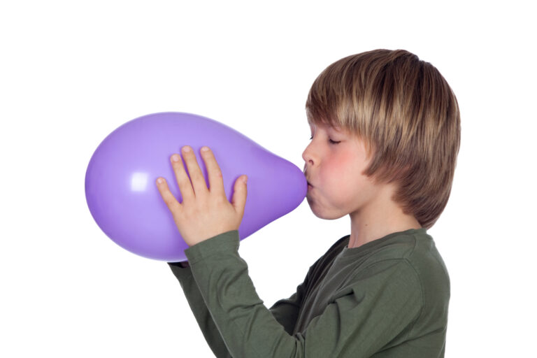 adorable preteen boy blowing up a purple balloon great activity for a rainy day